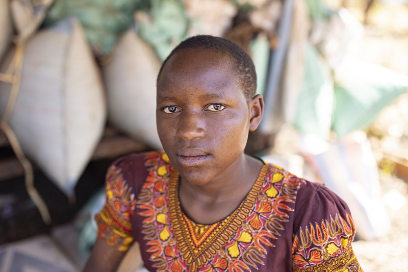 A teen girl in Kenya looks somberly at the camera.